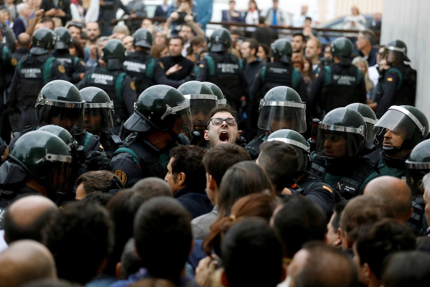 A man is swallowed by a sea of Spanish civil guard officers