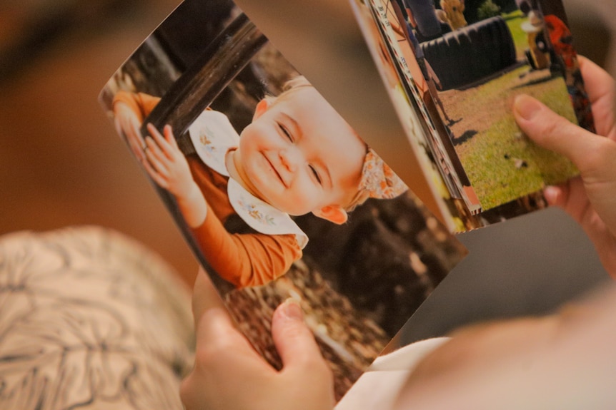 Woman holding photos of a young child.