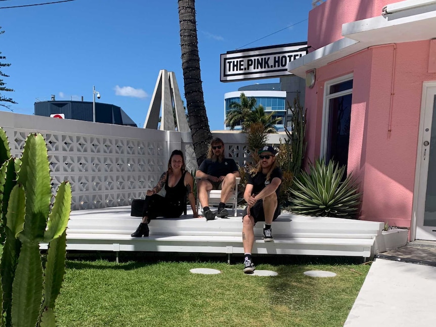Three people sit in the shade at a hotel