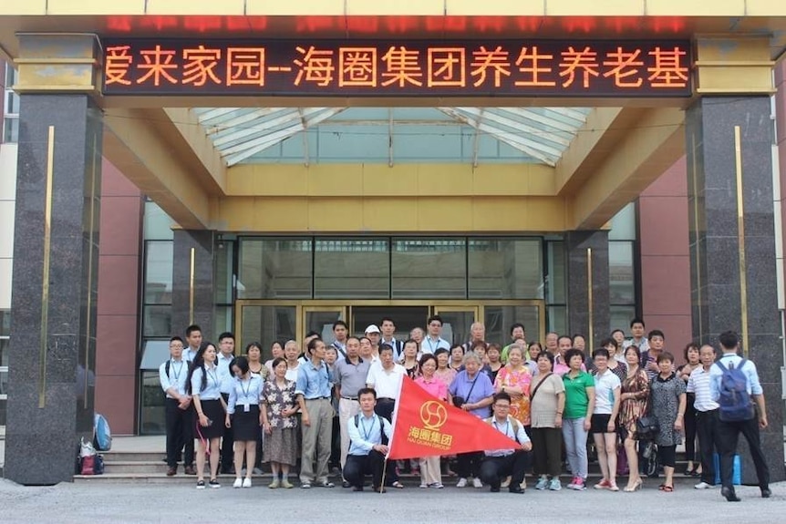 A group of Chinese people gather outside a building in China.