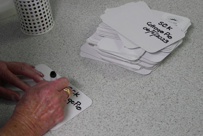 Une femme écrivant sur des morceaux de carton. 