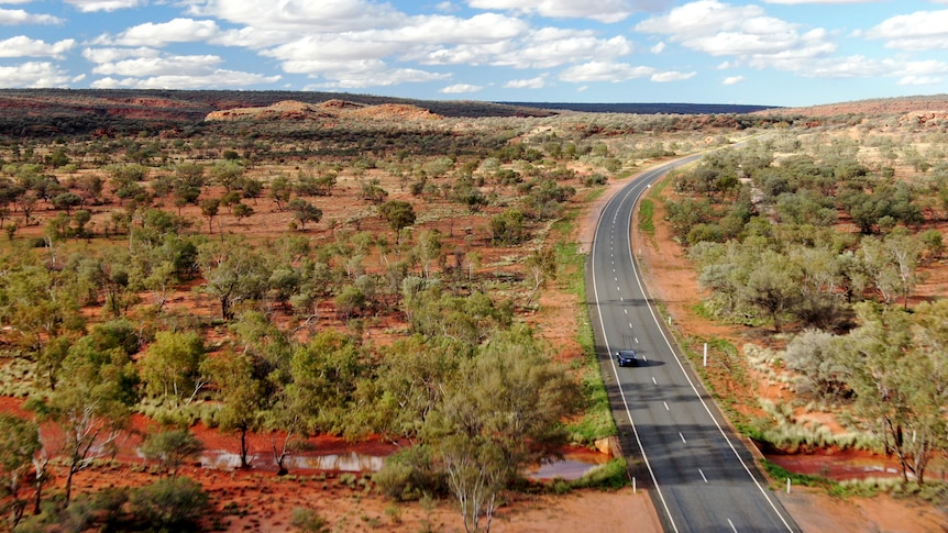 An electric vehicle drives on a remote road.