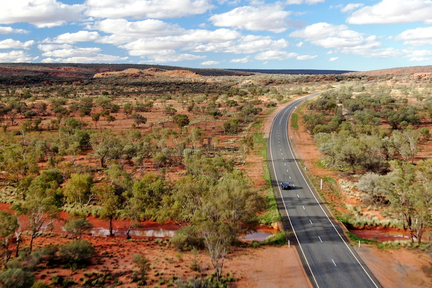 An electric vehicle drives on a remote road.