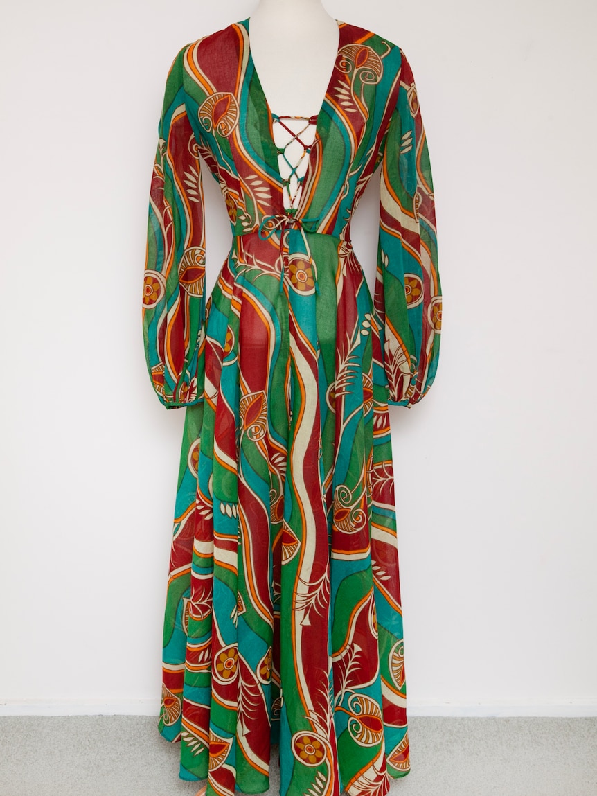 A floor length dress with a bold red, green and blue pattern with lacing at the bust