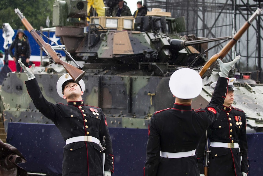 Men in US Marine Corps dress uniforms throwing rifles in the air