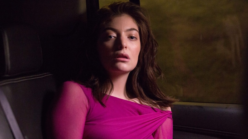 Image of NZ singer Lorde; singer dressed in purple dress, seated in car