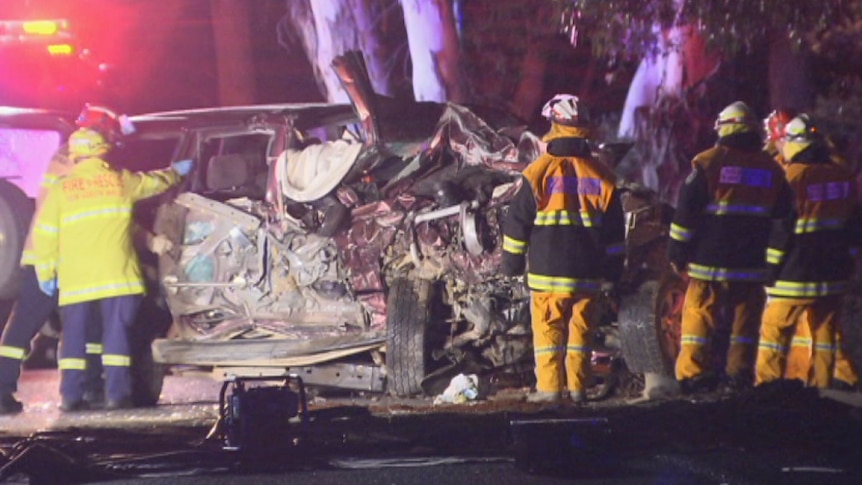 Emergency services workers next to a destroyed car.