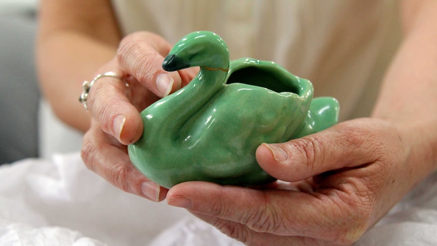 Close up of the porcelain swan in Claire's hands