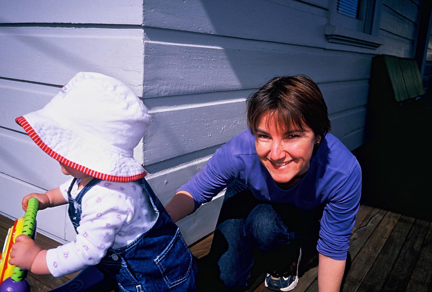 Rachel Wake squatting down and pushing a toddler on a bike