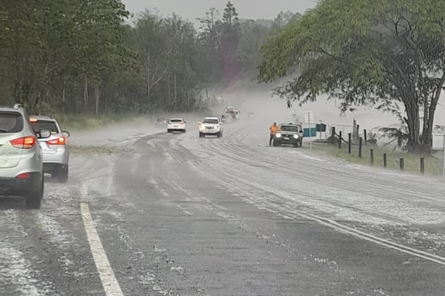 Cars pulled over on the side of a country road during a furious hailstorm.