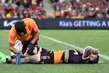 A man receives treatment on a knee injury during a rugby league match