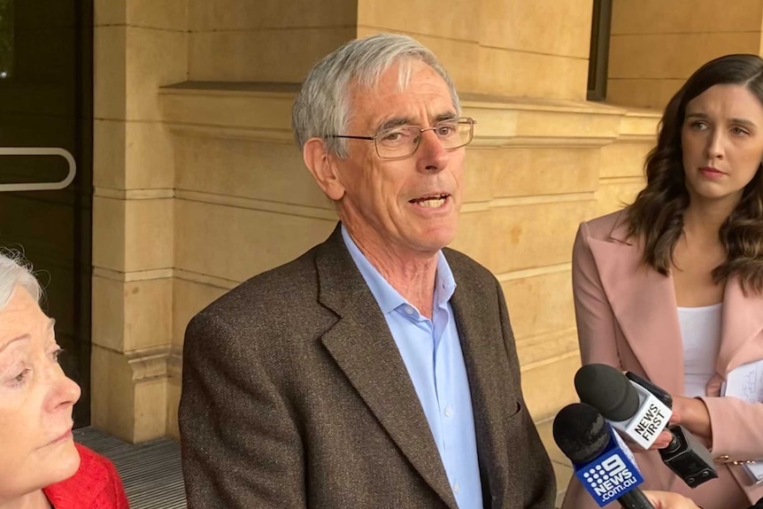 An older man speaking to female reporters