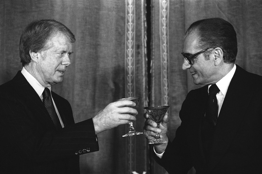 Black and white photo of two men toasting drinks.