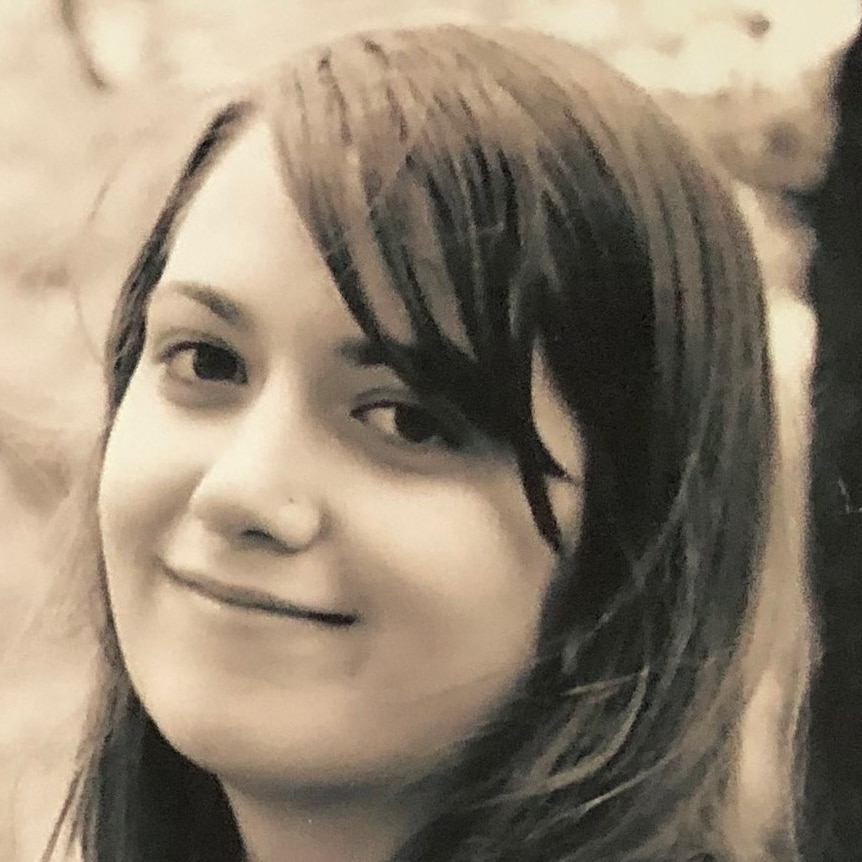 A black and white photo of a young woman with long dark hair who is smiling.