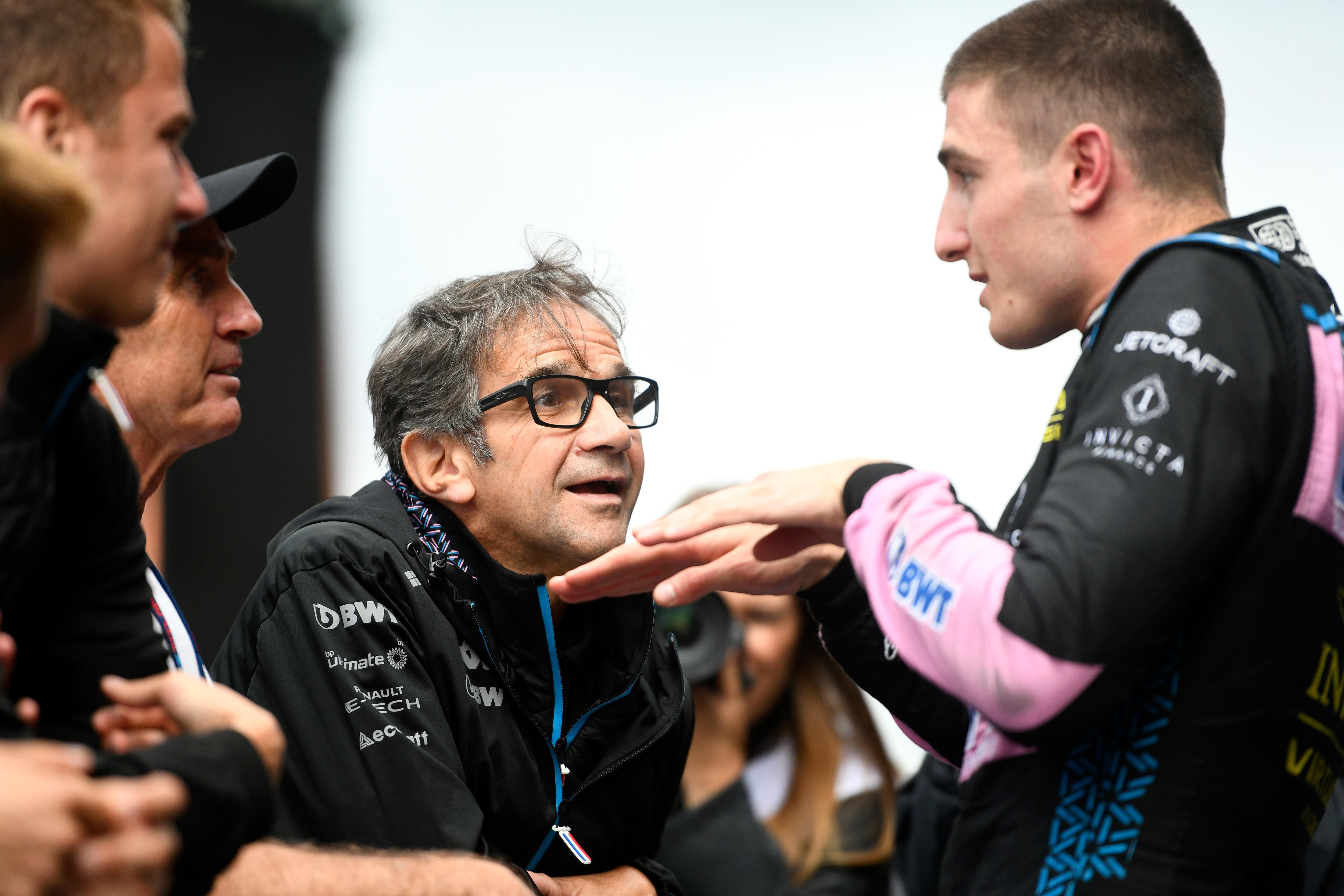 Racing driver in his race suit, gesticulating to his team member.