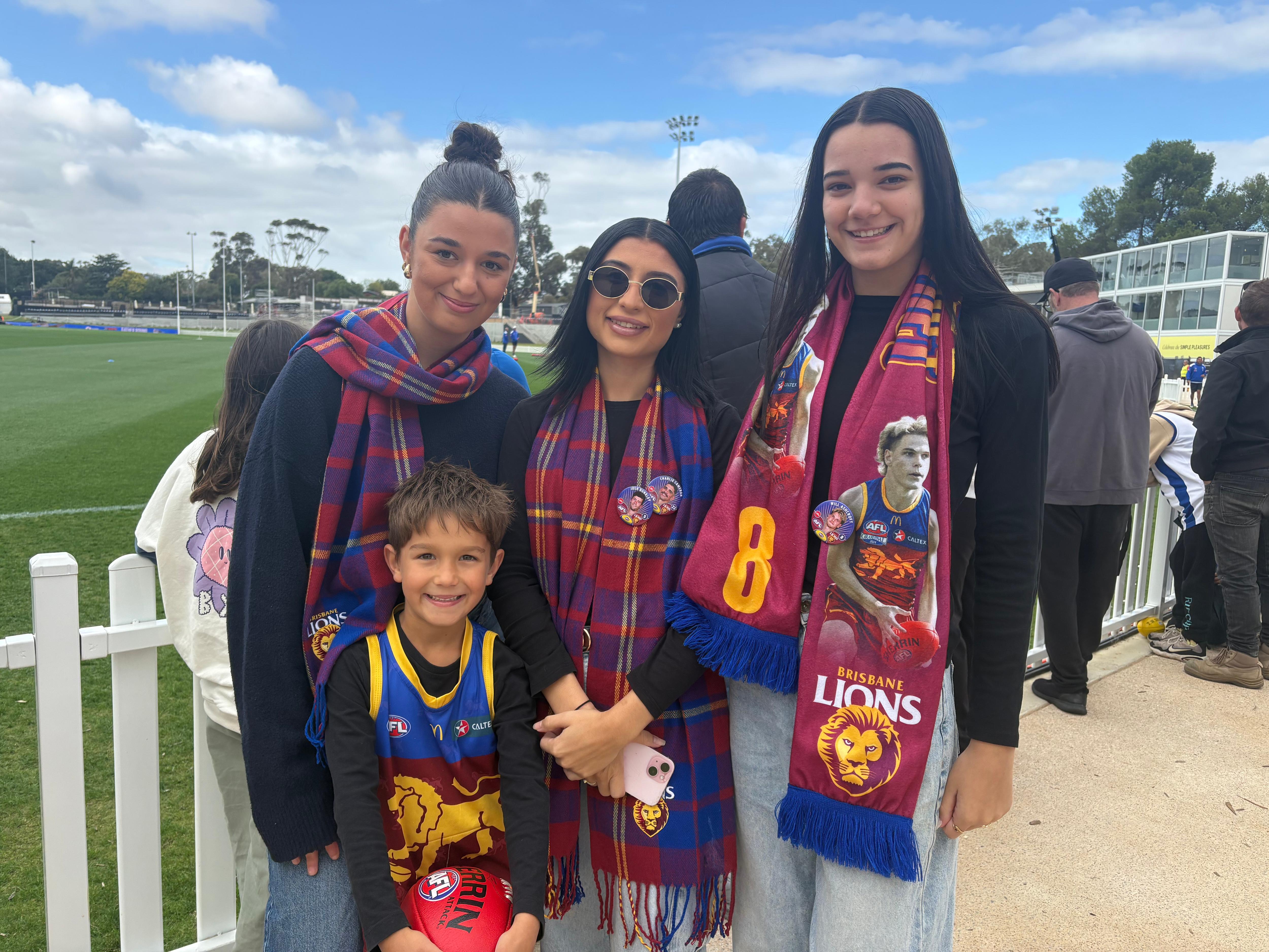Três mulheres jovens e um menino usando equipamento de íons de Brisbane ao lado de uma cerca branca