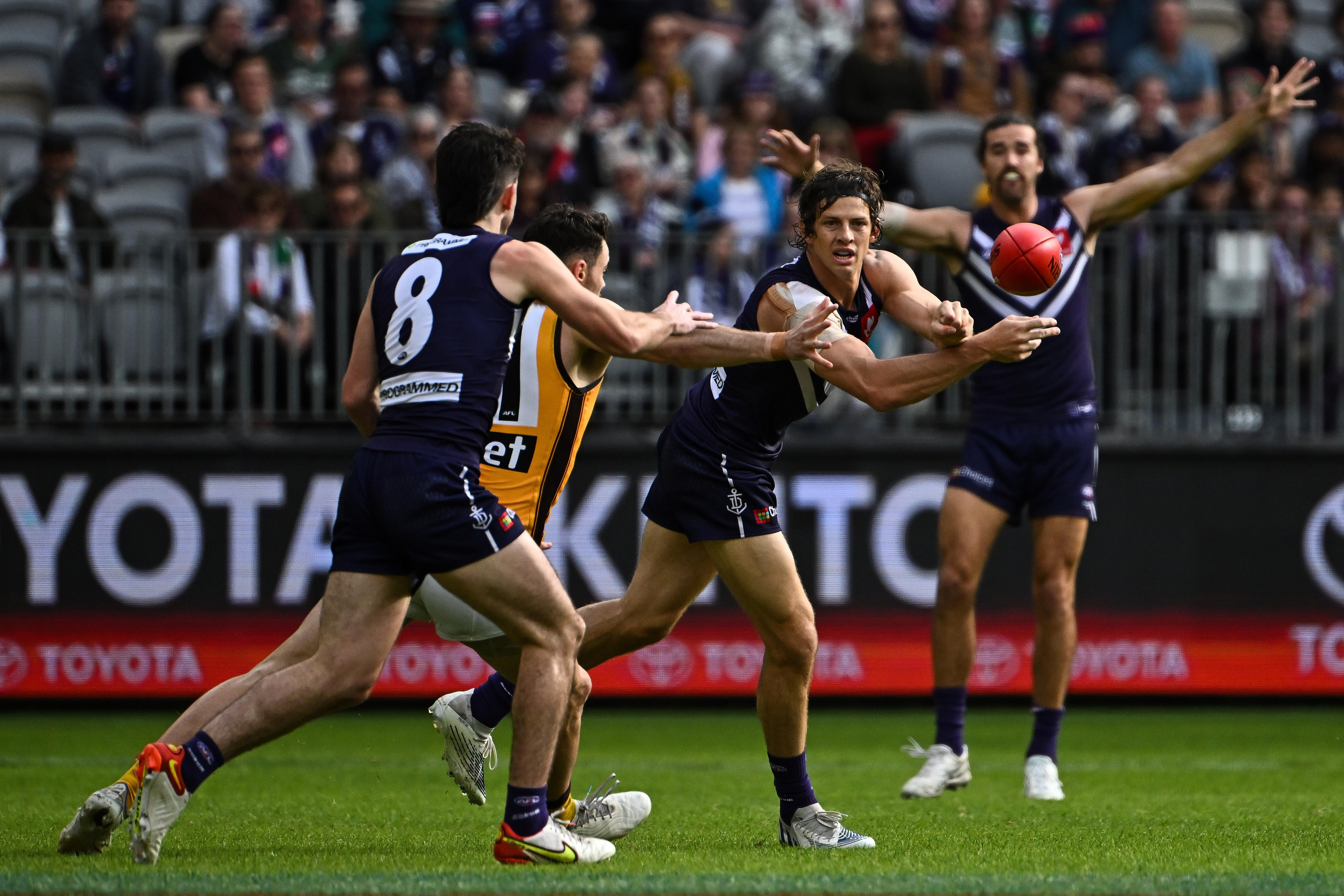 Nat Fyfe looks to give a handball off as teammates and opponents surround him