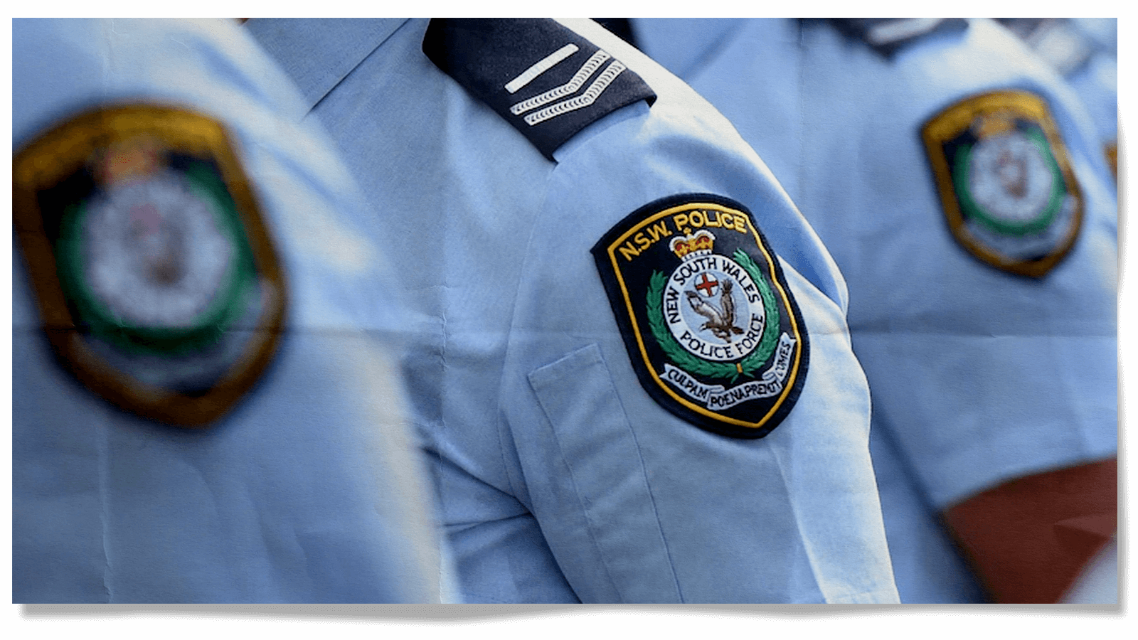 From close up, the shoulders of three NSW police officers in uniform