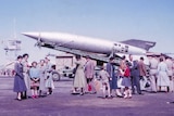 People stand in front of a V-2 rocket.