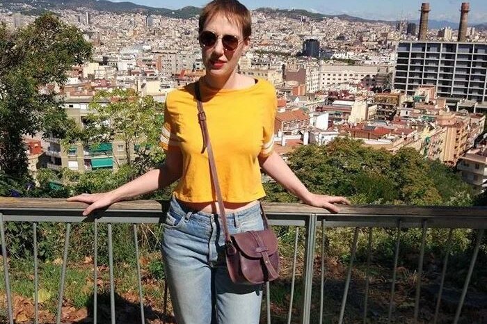 A woman with sunglasses on stands next to a railing.