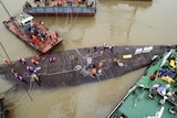 Rescue workers stand on the sunken cruise ship