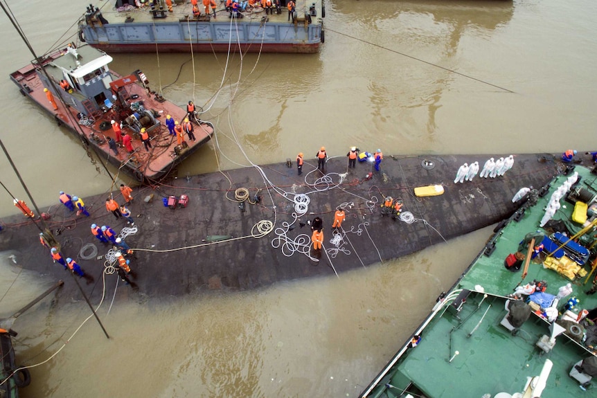 Rescue workers stand on the sunken cruise ship