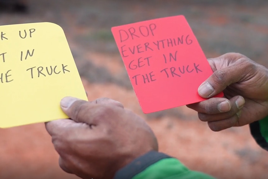 A man's hand holding cards that say "pack up, get in the truck" and "drop everything, get in the truck".