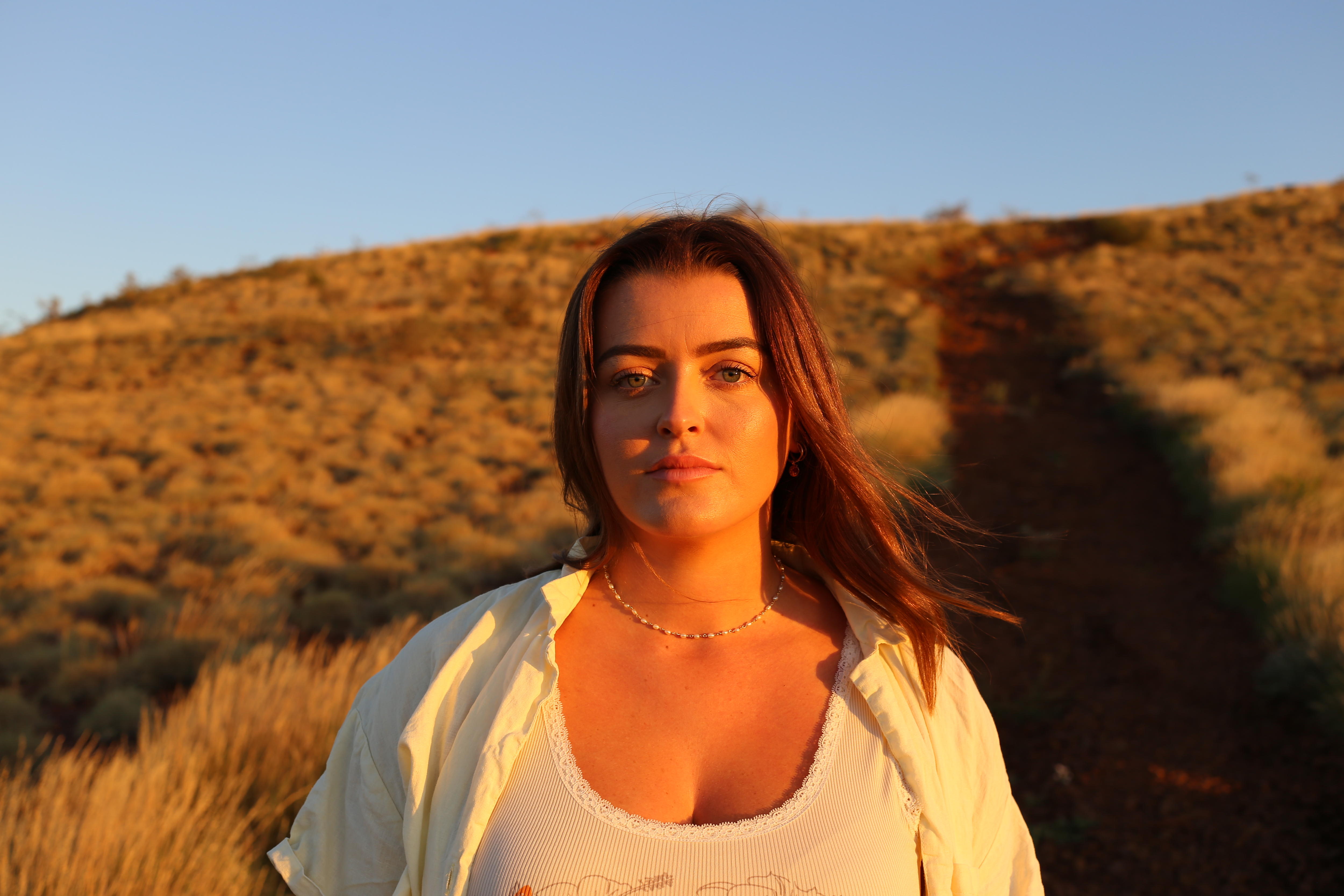 Girl looking straight at camera with spinifex bush in background.  
