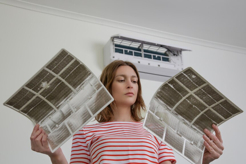 Stock image of a woman holding air conditioner filters.