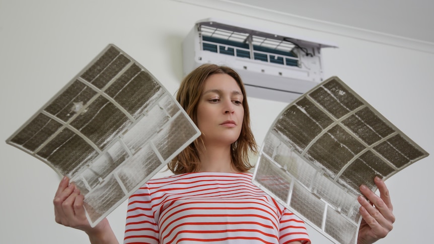 Stock image of a woman holding air conditioner filters.