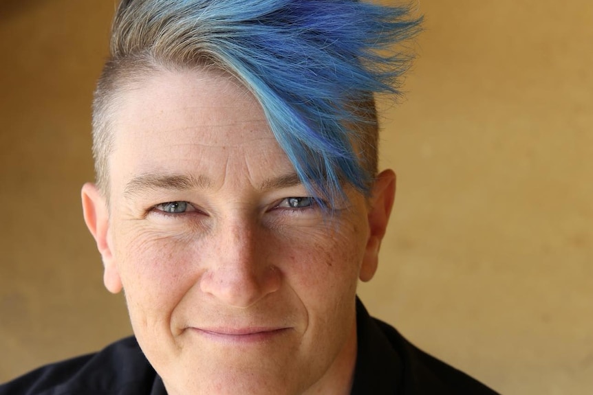A headshot of Casper Campbell with blue hair.