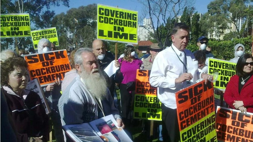 Protestors outside parliament carrying placards against cockburn lime and cement