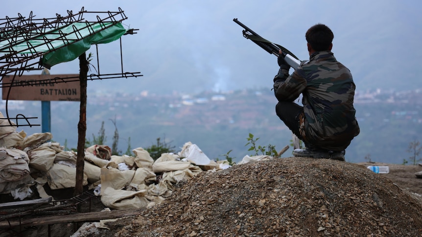 A soldier sits looking over a town.