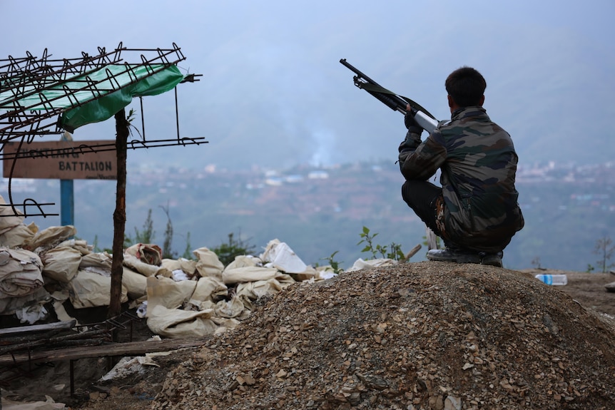 A soldier sits looking over a town.