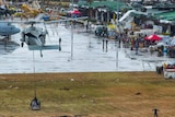 People affected by Typhoon Haiyan wait as a US Navy MH-60S Seahawk helicopter drops supplies.
