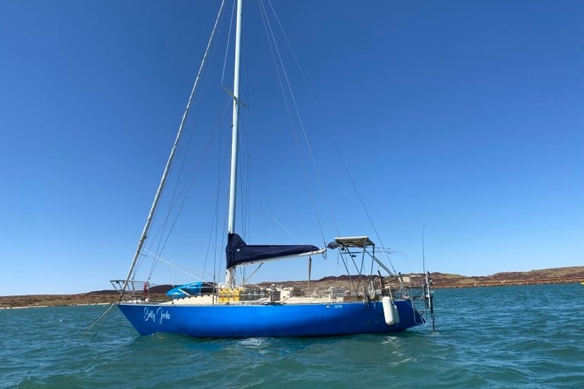 A blue yacht named Salty Jocks at rest on the ocean.