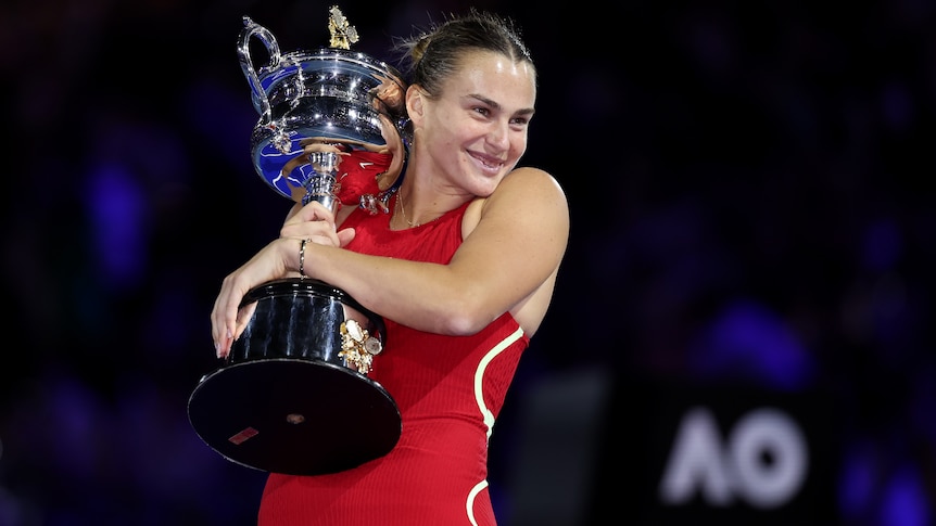 Aryna Sabalenka poses with the Daphne Akhurst Memorial Cup following her 2024 Australian Open victory.