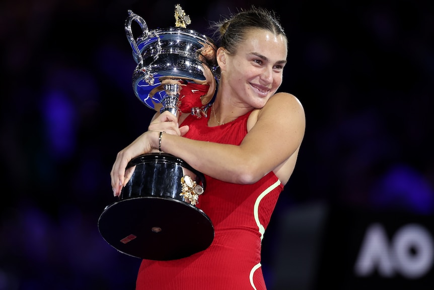 Aryna Sabalenka poses with the Daphne Akhurst Memorial Cup following her 2024 Australian Open victory.