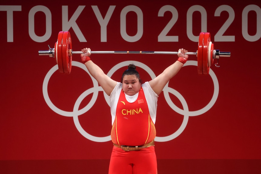 Li Wenwen lifts the bar above her head in the snatch position.