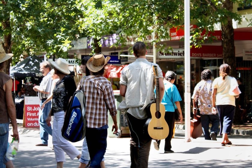 A country music fan, with guitar, walks down Peel Street during the Tamworth Country Music Festival.