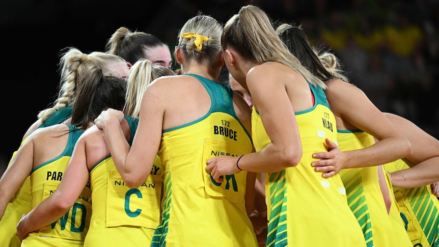 Diamond netball players in a huddle on the court.
