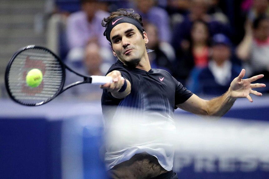 Roger Federer hitting a forehand with the net in the foreground at the US Open.