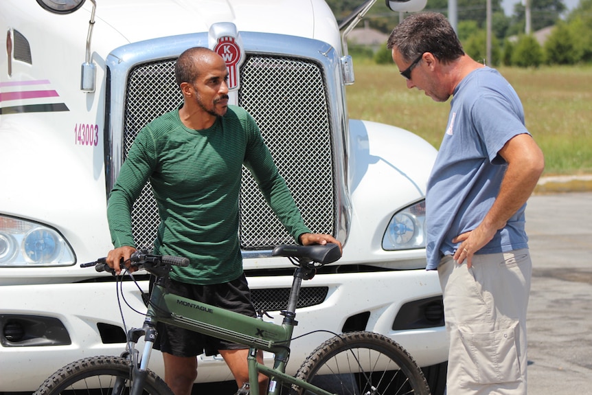 Siphiwe Baleka showing a fellow trucker a folding bike he uses
