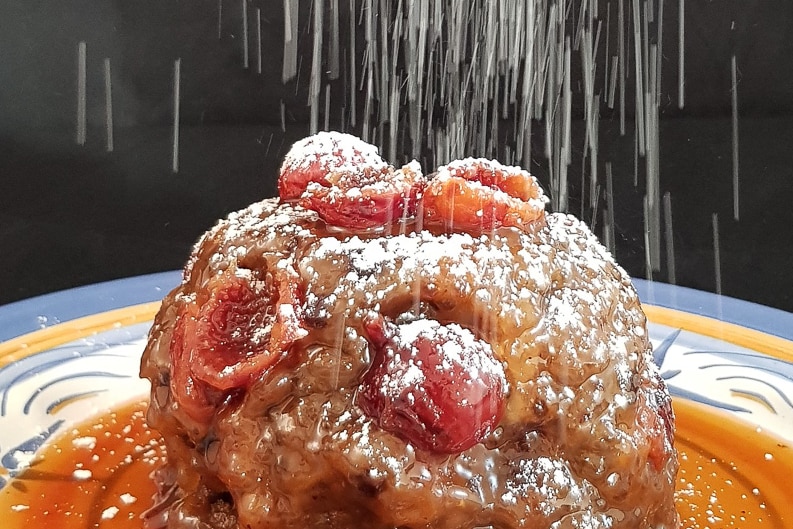 A quandong Christmas pudding, plated up with orange brandy sauce.