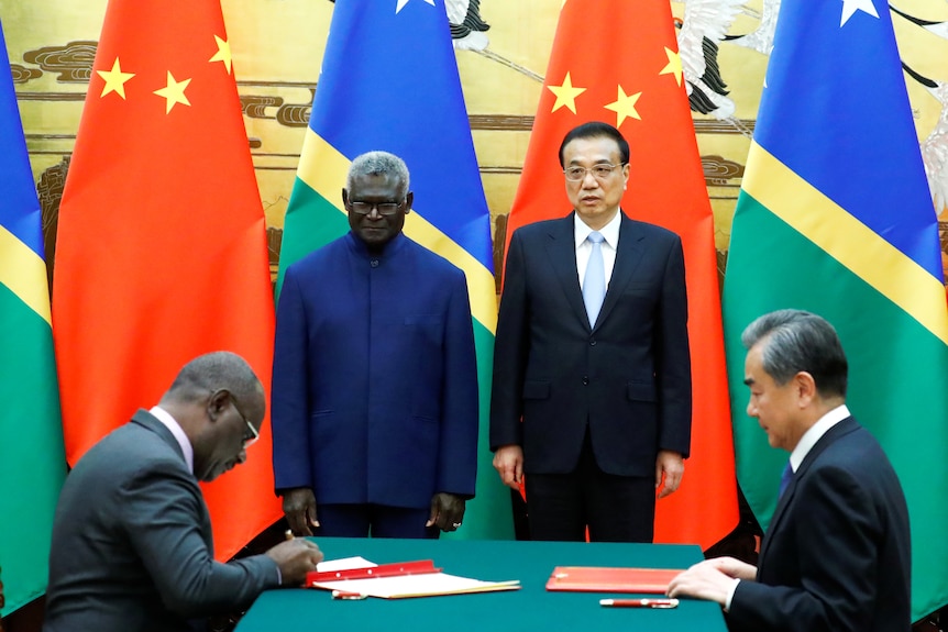 Four people around a table, signing.