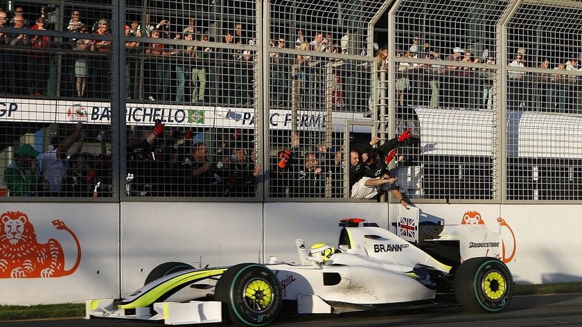 The Brawn crew behind the fence celebrate as Brawn driver Jenson Button crosses the finish line