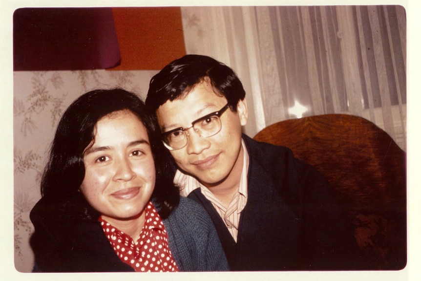 A Malaysian woman wearing a red spotted shirt poses for a photo with a man wearing dark rimmed spectacles and a dark sweater