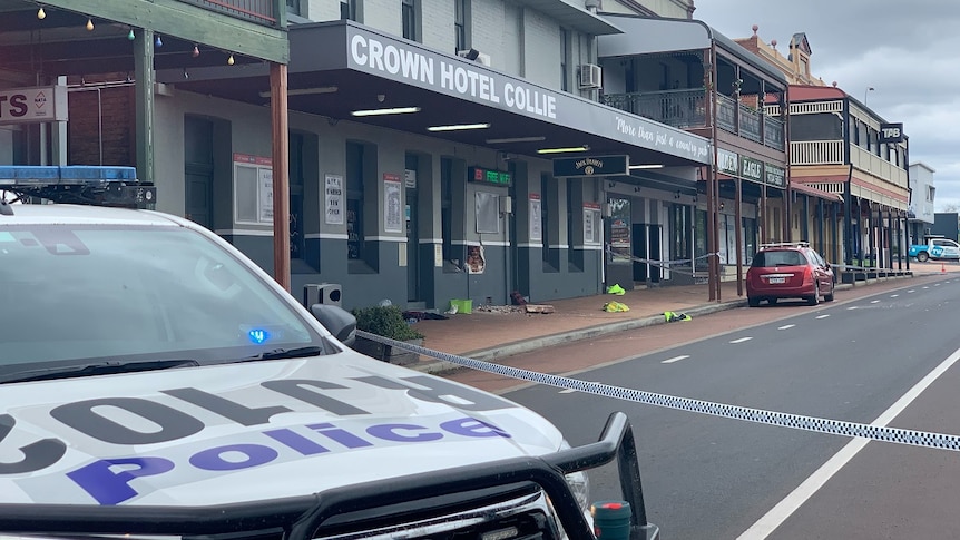 A police vehicle outside a police tape securing off the Crown Hotel Collie in a town's main street, red car parked outside.