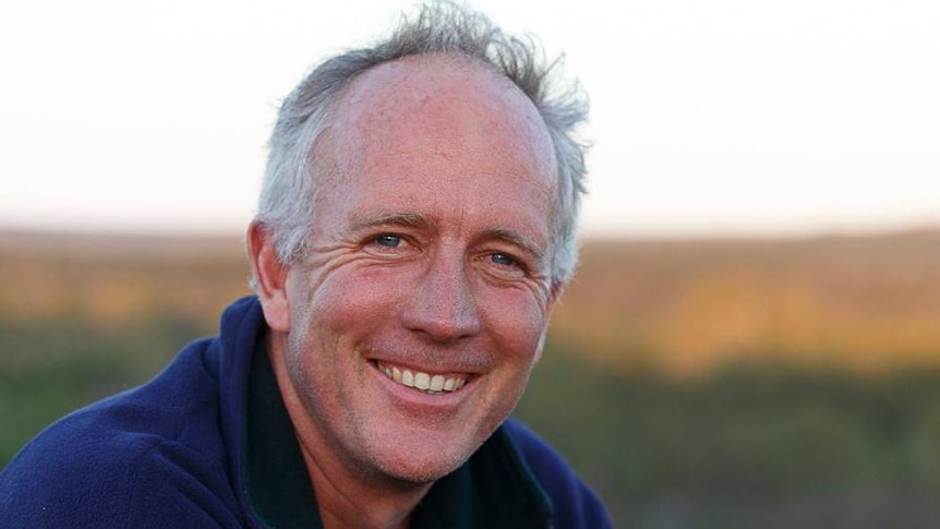 Matthew smiles at the camera. He is outdoors, background blurred.