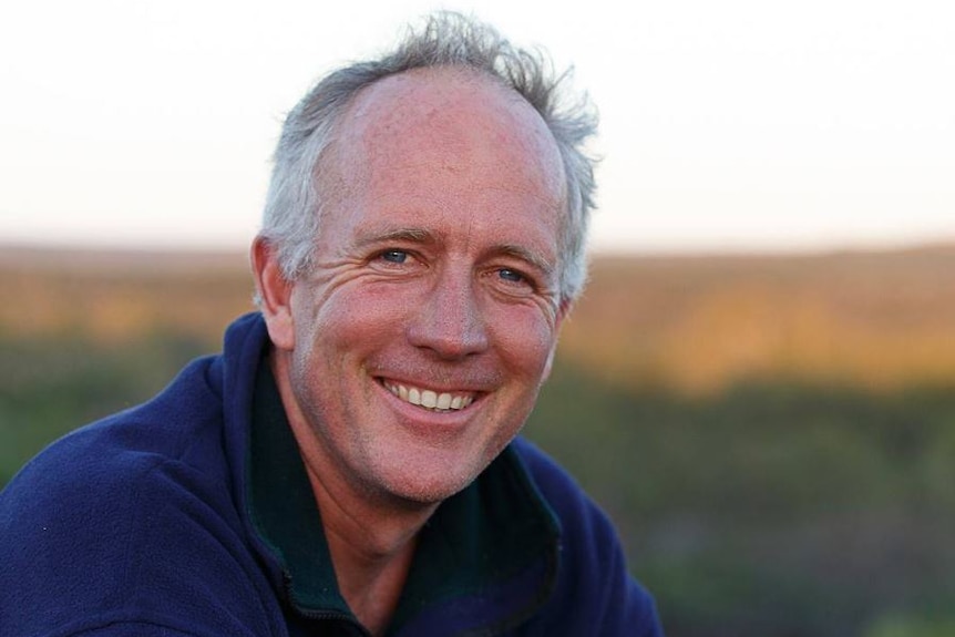 Matthew smiles at the camera. He is outdoors, background blurred.